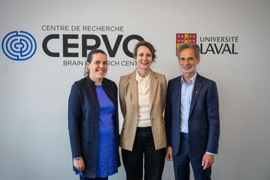 Three people stand smiling in front of a wall with the Centre de recherche CERVO Brain Research Centre and Université Laval logos.