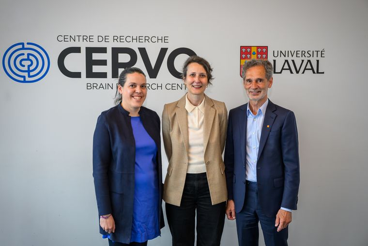 Three people stand smiling in front of a wall with the Centre de recherche CERVO Brain Research Centre and Université Laval logos.