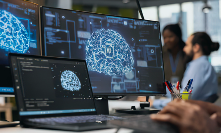 A workstation with multiple monitors displaying brain-like neural network visuals and code, with a person working at a computer in a modern office environment.